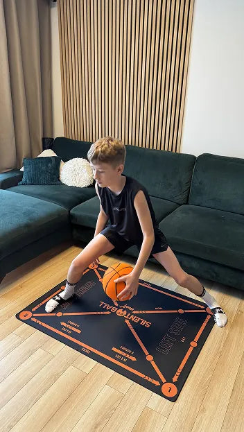 Child holding a silent ball basketball on training a mat with 'SilentBall Academy' branding in a living room.